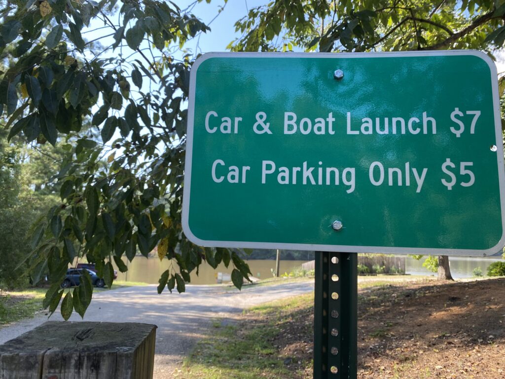 Posted fee sign at the Bear Creek Marina boat ramp reading Car & Boat Launch $7 and Car Parking Only $5